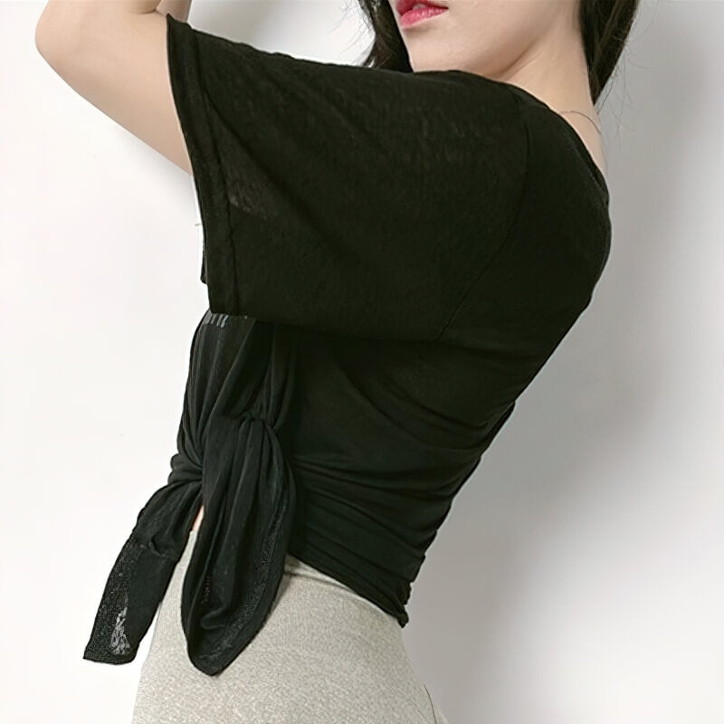 Woman wearing a stylish black cropped sports top with side cut, perfect for yoga. Made of nylon and spandex, featuring short sleeves.